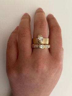 a person's hand with two gold rings on their fingers and one has a diamond in the middle