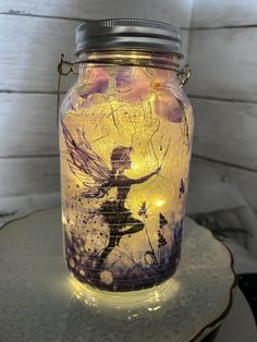 a jar with a fairy on it sitting on top of a table