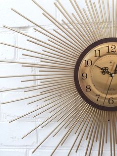 a clock that is on the side of a brick wall with gold rays around it