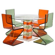 an orange and green glass table with four chairs around it, all stacked on top of each other