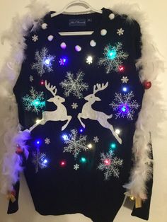 an ugly sweater with lights and snowflakes is hanging on a white wall in front of it