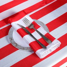 a red and white striped table cloth with silverware on it, along with napkins