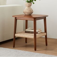 a small table with a flower in a vase and books on the floor next to it