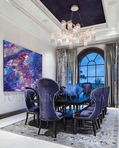 a dining room table with blue chairs and a chandelier hanging from the ceiling