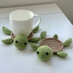 two crocheted sea turtle coasters and a coffee cup on a white table