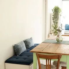 a kitchen table and bench in front of a window with potted plants on it