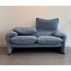 a blue couch with two pillows on it in front of a white wall and floor