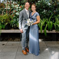 a man and woman standing next to each other in front of some plants at a wedding