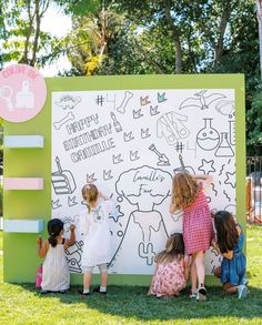 children are drawing on a sign in the grass