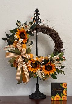 a sunflower wreath on top of a table next to a book and candle holder