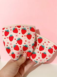 someone is holding two small pouches with strawberries on them, one in the shape of a heart