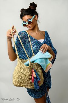 a woman wearing sunglasses and carrying a straw bag with her hand on the shoulder,