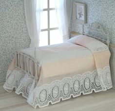 a small bed in a room with blue wallpaper and white lace on the bedspread