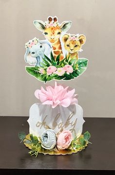 two giraffes and one zebra are on top of a cake with flowers