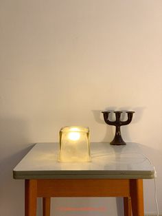 a table with a lit candle on it and a small vase sitting next to it