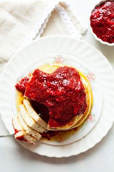 a plate with pancakes covered in strawberry jam