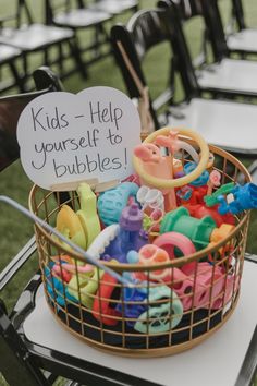 a basket filled with lots of toys sitting on top of a table next to chairs