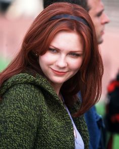 a woman with red hair is smiling at the camera