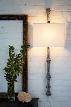 a lamp that is on top of a table next to a mirror and a plant