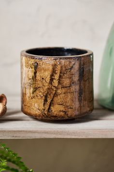 a wooden cup sitting on top of a shelf next to a vase and some plants