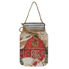 a mason jar with a red barn and wreath hanging from the side on a rope