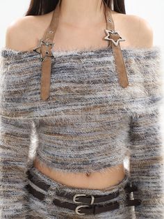 a close up of a person wearing a sweater and belted skirt with metal decorations on it