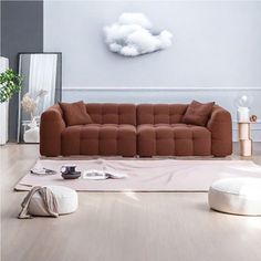 a living room with a brown couch and white rugs on the wooden flooring