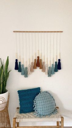 the wall hanging is decorated with blue and white tassels, which are hung above a bench