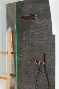 a shower head and hand shower in a bathroom with grey tile on the back wall