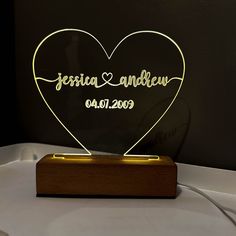 a heart shaped light up on top of a wooden stand with the words, jesus and andrew written in cursive writing