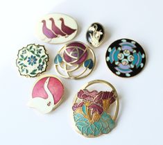 six different colored brooches sitting on top of a white table next to each other