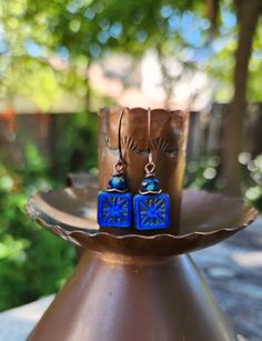 The centerpiece for these stunning boho earrings is a cobalt blue tile bead with a gorgeous starburst.  Another petite pair of earrings! Simply gorgeous Czech glass! Love the look! These unique beauties are just under two inches in length, including the copper hooks.  The Czech glass square bead is accented with a complimentary Rondelle bead and wavy copper disc.  These square starburst beads are some of my favorite beads because of the richness of the color and the design.  One of a kind. Lightweight! Petite. Handmade. Smoke free artist studio. Artisan Blue Drop Earrings, Artisan Blue Earrings For Festival, Artisan Blue Nickel-free Earrings, Blue Earrings With Ear Wire For Festival, Adjustable Blue Earrings For Festival, Nickel-free Blue Earrings For Festival, Blue Drop Earrings For Festival, Blue Pierced Earrings For Festival, Cobalt Blue Tile