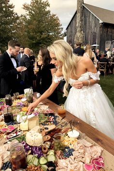 a bride and groom are cutting their wedding cake at the table with many other people in the background