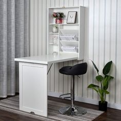 a white desk and chair in front of a striped wallpapered room with a potted plant