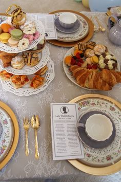 a table topped with plates and cups filled with pastries on top of each other