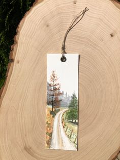 a piece of wood with a tag hanging from it's side next to a tree