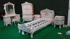 a white bed sitting next to a wooden dresser and chair on top of a green carpeted floor