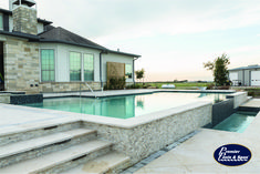 a large swimming pool with steps leading up to it and a house in the background