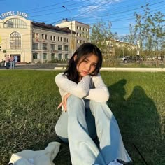 a woman sitting on the grass in front of a building