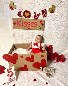 a baby is sitting in a box with hearts