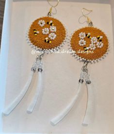 the earrings are decorated with beads and sequins in orange, yellow and white colors