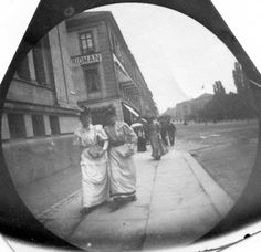 an old black and white photo of two women walking down the street