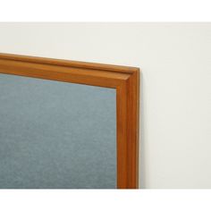 a mirror on the wall in front of a white wall with blue carpeting and a wooden frame