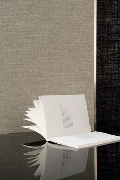 an open book sitting on top of a table next to a black and white wall