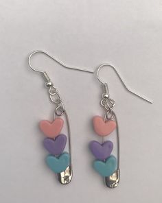 three hearts dangling from a pair of spoons on a white surface with silver earwires