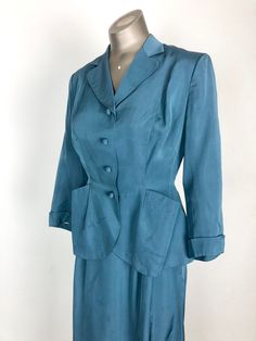 "1940's teal suit from Finland has a fitted jacket and a-line pencil skirt. The jacket has a rounded lapel, angular pockets at the hips, cuffed sleeves, and a button front with covered buttons. The jacket is tailored with shoulder pads, full white rayon completely hand stitched lining, double princess seams for fit, and lots of beautiful handwork including hand-stitched welt button holes. The skirt has pleating at the waist front waist, and single side pleat in the back. There's a metal side zip Vintage Fitted Blue Suits, Vintage Blue Skirt Suit For Formal Occasions, Blue Fitted Vintage Suit, Vintage Fitted Skirt Suit With Notch Lapel, Fitted Vintage Blue Suits, Spring Vintage Tailored Suits, Vintage Skirt Suit With Button Closure For Formal Occasions, Vintage Formal Skirt Suit With Button Closure, Classic Fitted Skirt Suit With Pockets