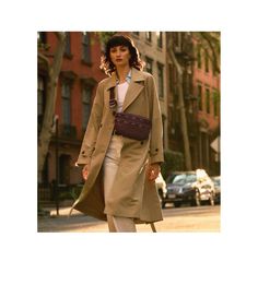 a woman is walking down the street wearing a trench coat