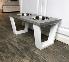 two metal bowls are sitting on top of a concrete table in the middle of a kitchen