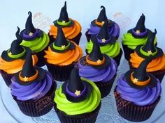 cupcakes decorated with witch hats and witches'hat decorations on a glass platter