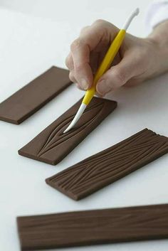 a person with a pen writing on some chocolate strips